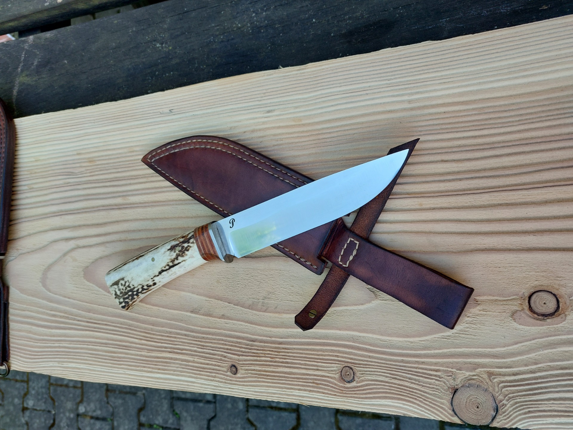 Velký Bushcraft - nerez ocel N690 , nerez záštita, střenka kombinace kůže a parohu , ukončeno záslepkou ze stabilizovaného javoru. Pouzdro z hověziny .